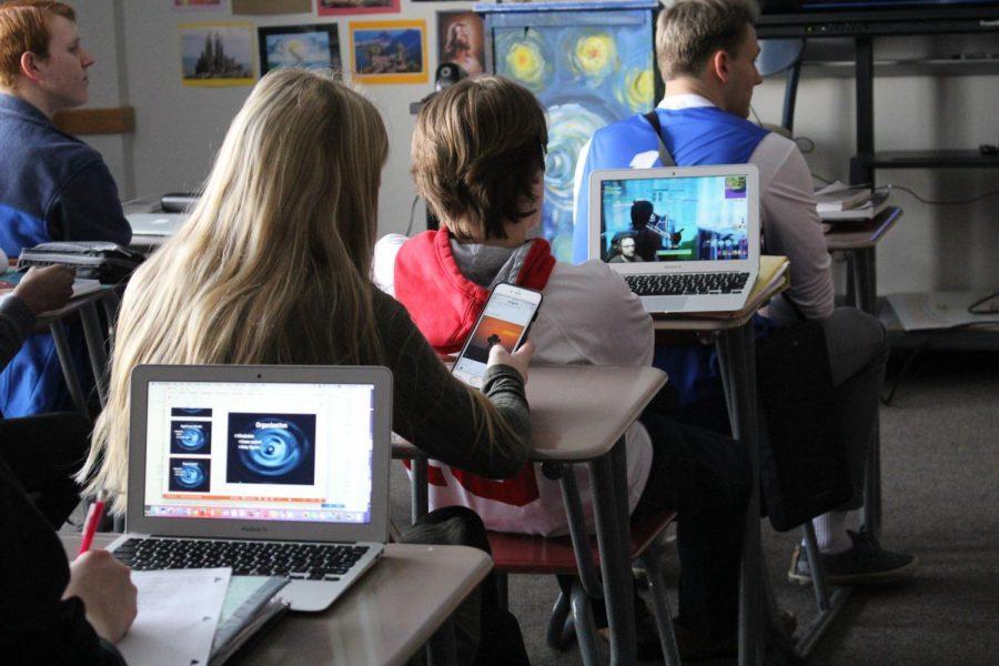 A schoolgirl is distracted by her phone during class