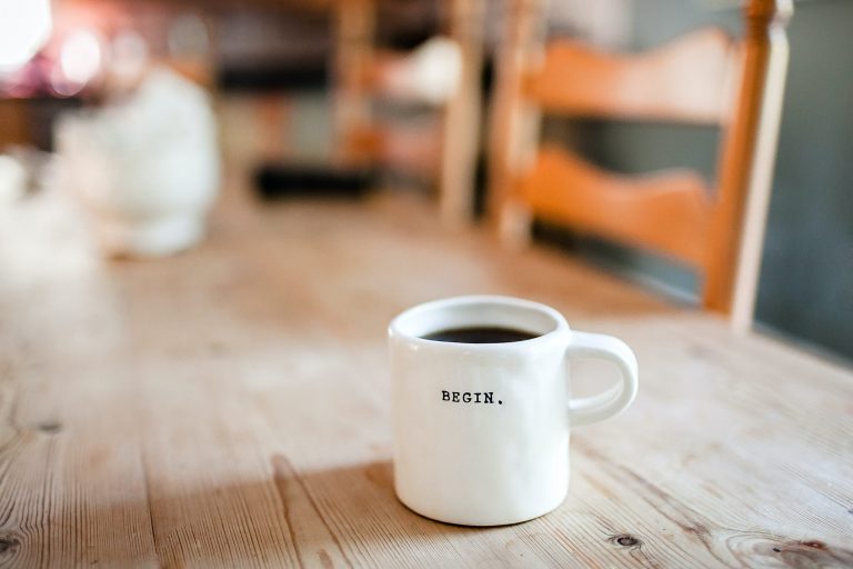 A cup of coffee with a quote on it which says to begin